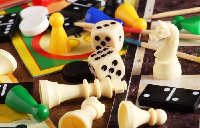 Various board game pieces such as form dominoes, chess, counters and dice.