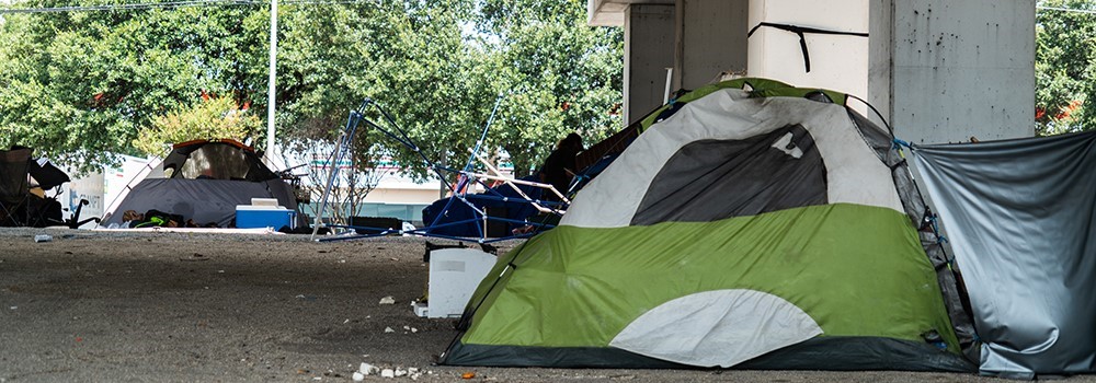 A tent at the foreground, under a bridge and another tent in the background.